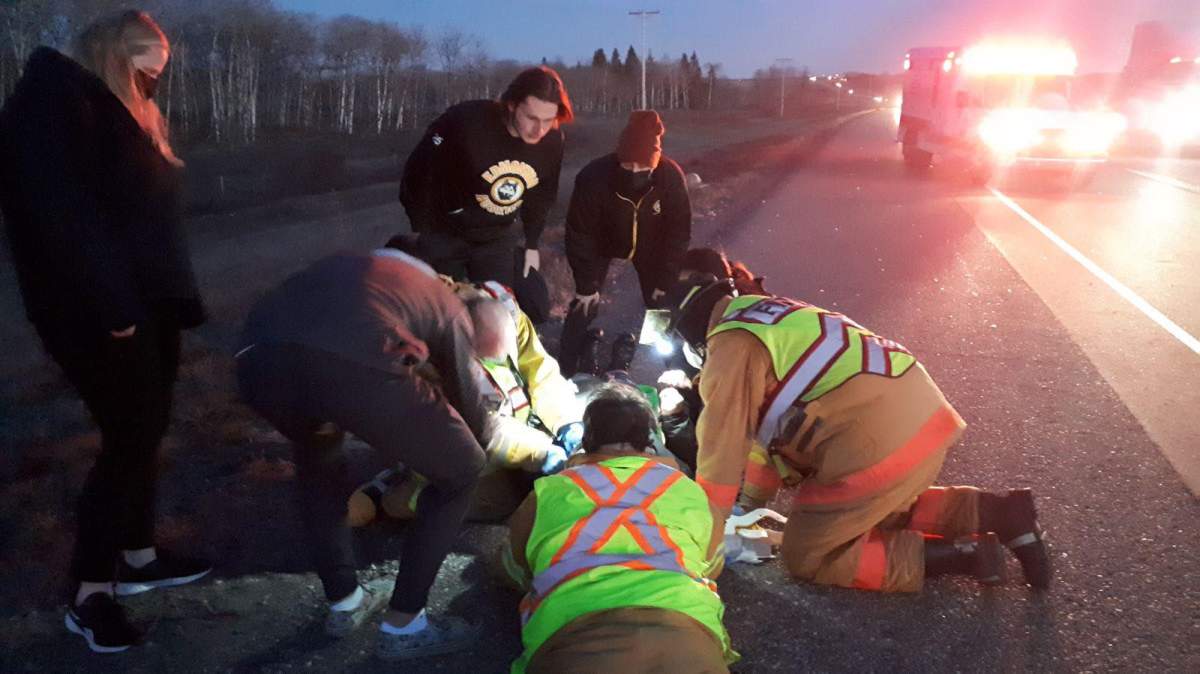 Members of the Edmonton Huskies football team helping a motorcycle rider who hit a deer on a highway near Borden, Sask. on Sunday, Nov. 7, 2021.