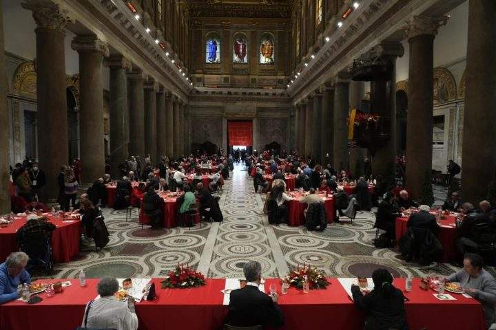 People sit at a Christmas day soup kitchen for fragile people, the poor, the homeless, and asylum seekers, set by the Sant’Egidio Community, at the Santa Maria in Trastevere Basilica in Rome, Saturday, Dec. 25, 2021.