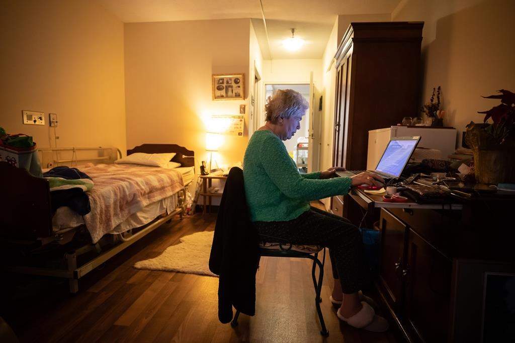 Inglewood Care Centre resident Janet Baxter, 82, uses her computer in her room at the long-term care home in West Vancouver, on Thursday, December 16, 2021. The COVID-19 pandemic has prompted a rethink of how long-term care facilities are designed to prevent outbreaks of infectious diseases that can easily spread in crowded quarters, isolating residents and closing them off from family visitors. THE CANADIAN PRESS/Darryl Dyck.
