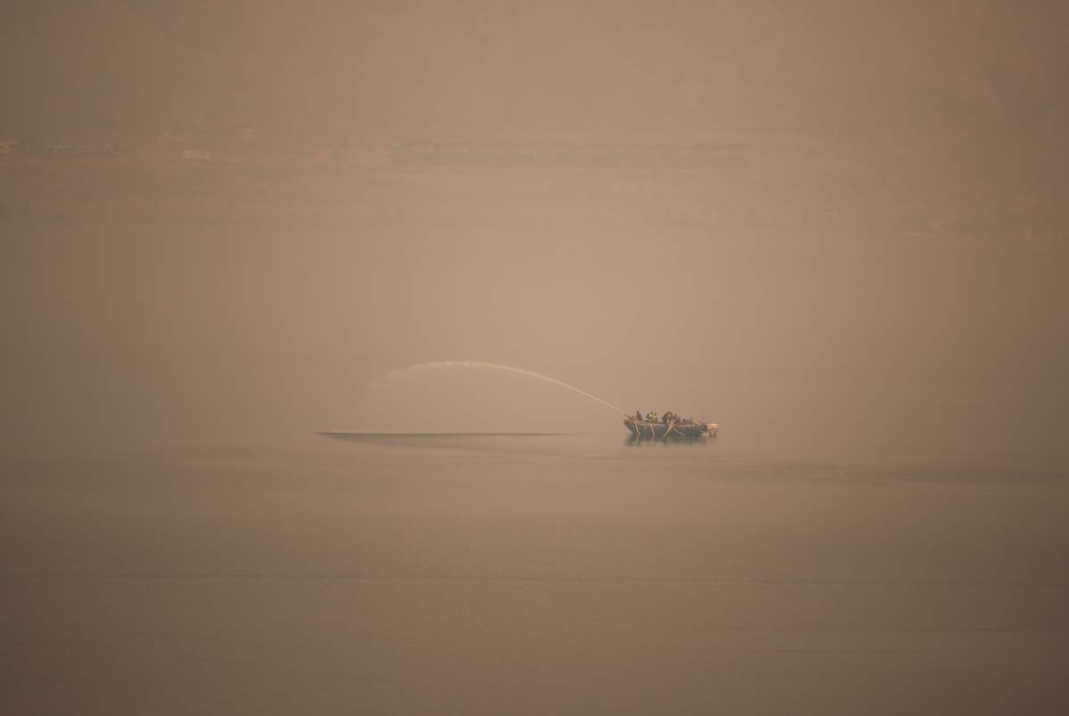 Shrouded in wildfire smoke, a firefighting boat is tested on Kamloops Lake in Savona, B.C., on Sunday, Aug. 15, 2021.