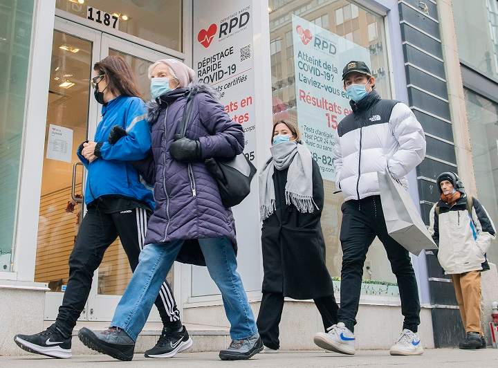 People walk by a COVID-19 rapid testing business in Montreal, Saturday, Dec. 4, 2021. 
