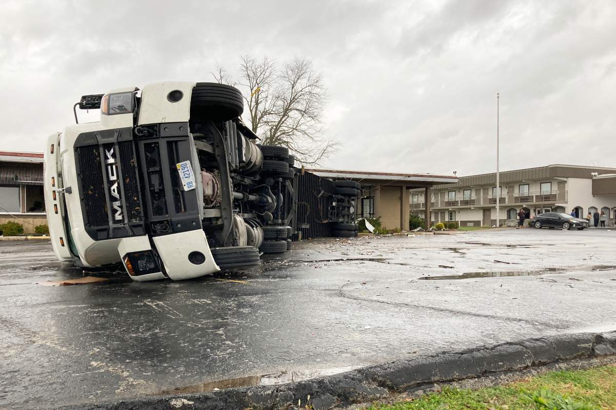 A large semi trailer is flipped over and pushed against a building in Bowling Green, Ky., on Saturday, Dec. 11, 2021.