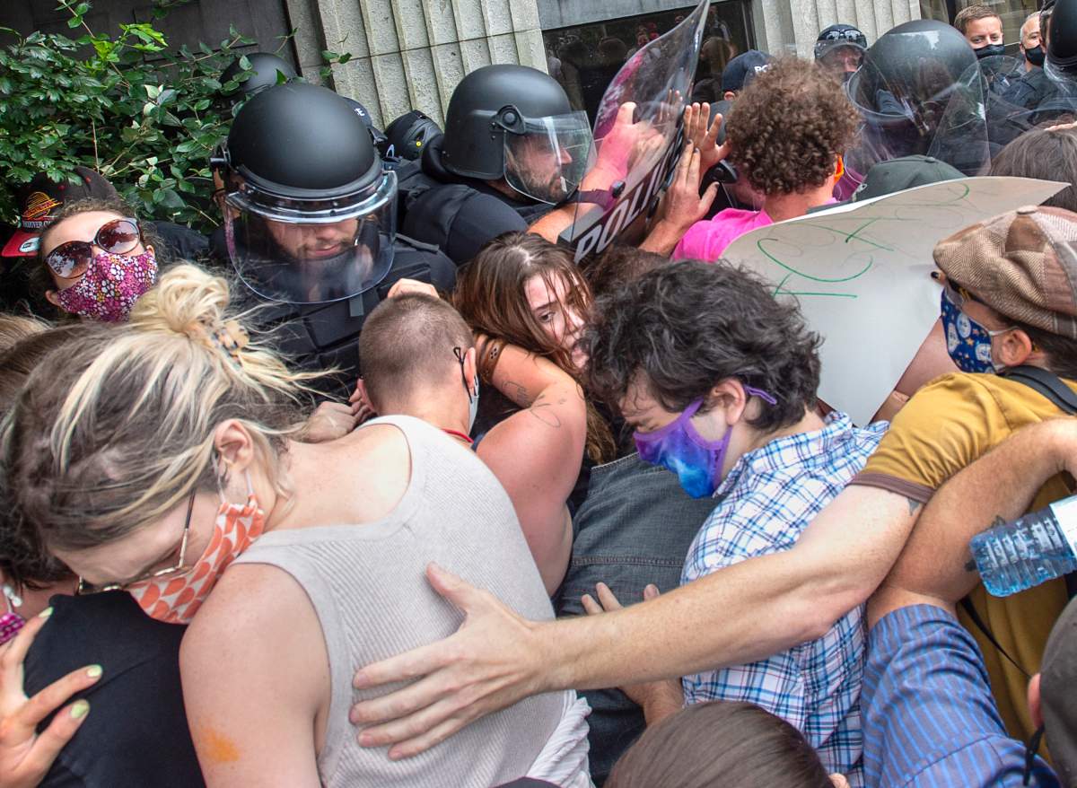 Protesters jostle with police at a protest after the city removed tents and small shelters for homeless people in Halifax on Wednesday, Aug. 18, 2021.