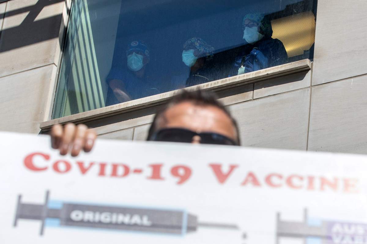 Healthcare workers watch from as window as demonstrators gather outside Toronto General Hospital, on Monday, Sept. 13, 2021, to protest against COVID-19 vaccines, COVID-19 vaccine passports and COVID-19 related restrictions.