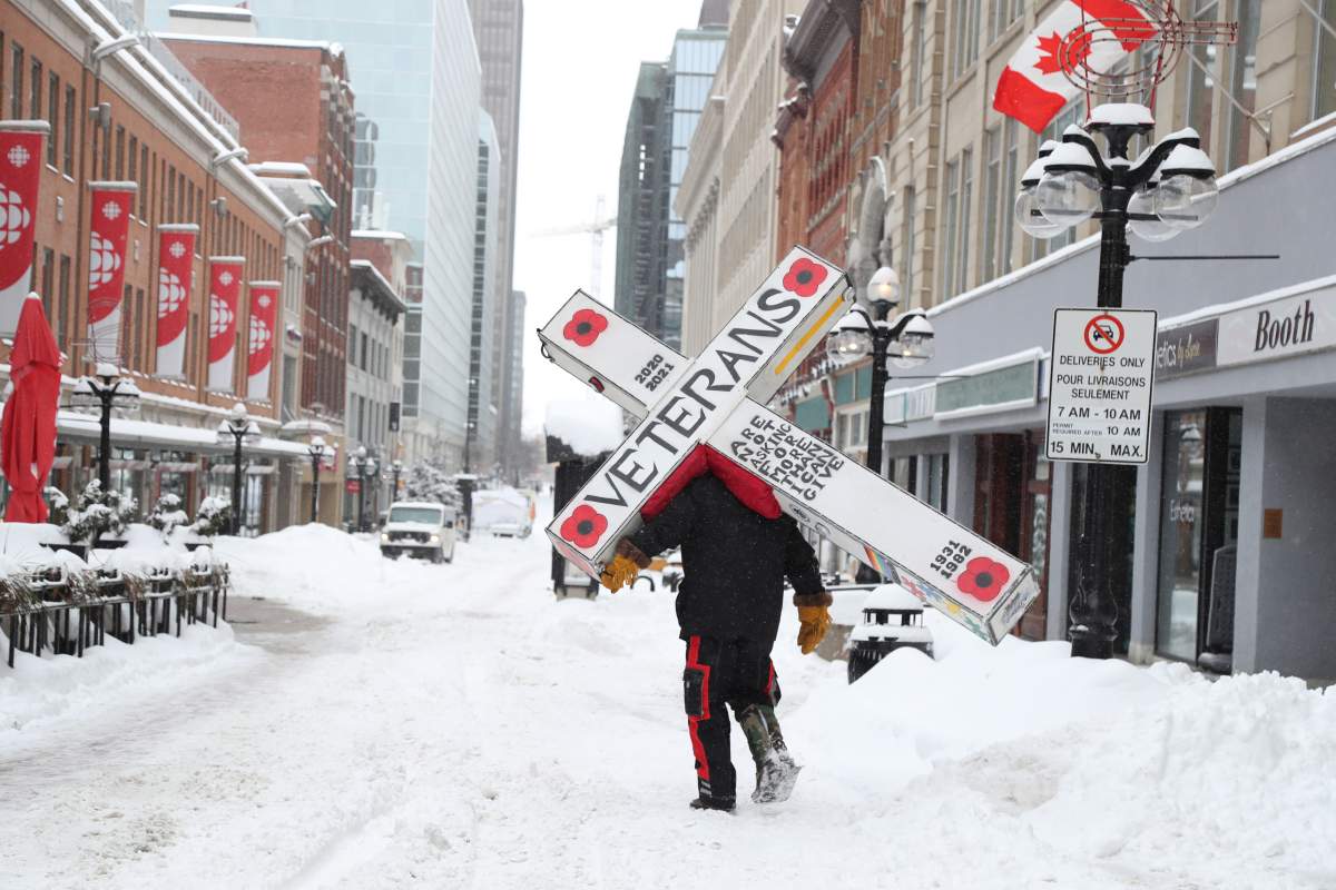 Warren Parke walks along Sparks St. in downtown Ottawa with an 80-pound cross on his back to bring awareness to issues facing veterans and First Nations communities on Tuesday, Feb. 16, 2021. Parke set off walking from his home in Kelowna, B.C. on Dec. 17 and arrived in Ottawa, the end of his journey, on Feb. 15.