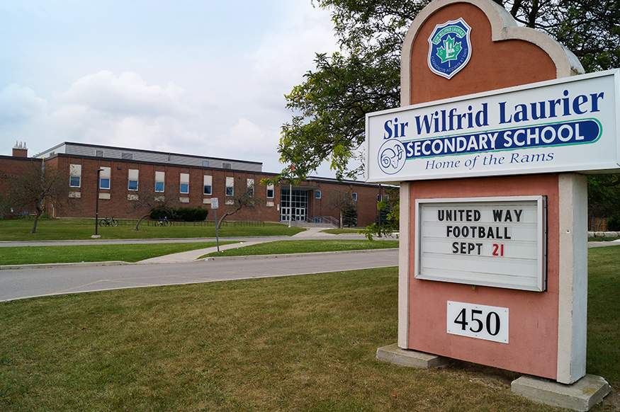 The foreground shows a sign for a school, which can be seen in the background.