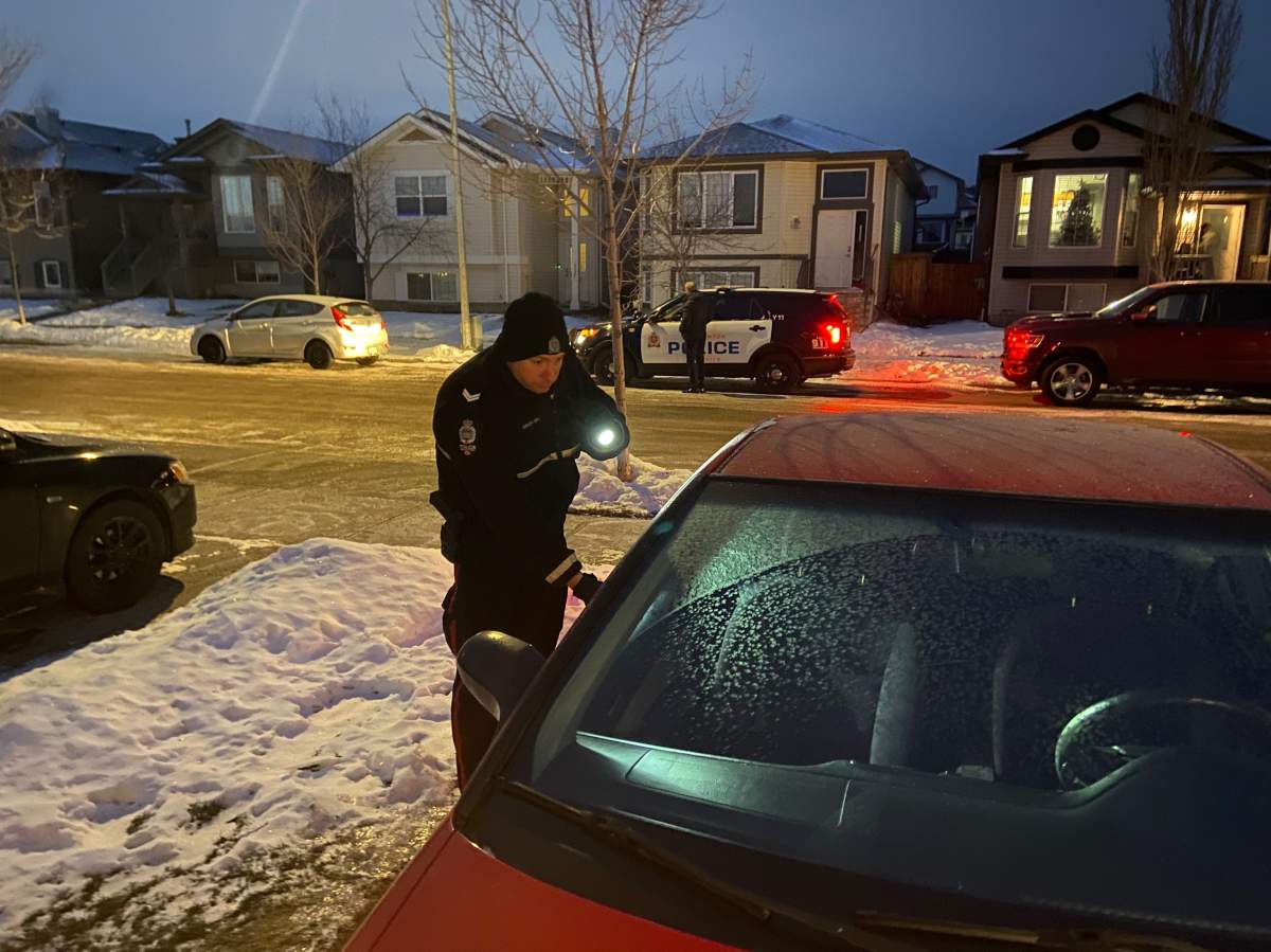 Edmonton Police Service Const. Brett Earley inspecting a vehicle to see if it’s been left idling and unlocked in the northeast neighbourhood of Brintnell on Tuesday, December 7, 2021.