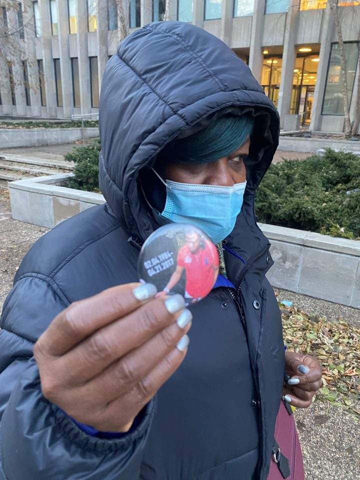 Angela Pinnock holds up a button with a photo of her son on it.