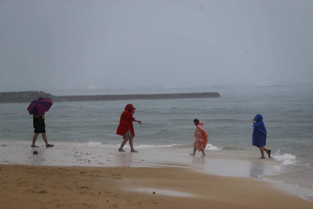 Beach goers play in the rain on Waikiki Beach, Monday, Dec. 6, 2021, in Honolulu.