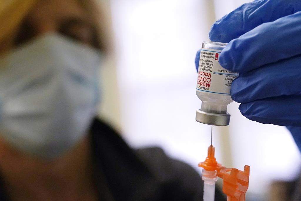 FILE - Pharmacist Kenni Clark prepares a booster dose of the Moderna COVID-19 vaccine during a vaccination clinic at City of Lawrence's "The Center," which serves seniors, families and the community, Wednesday, Dec. 29, 2021, in Lawrence, Mass. U.S. regulators, on Friday, Jan. 7, 2022, are shortening the time that people who received Moderna's COVID-19 vaccine have to wait for a booster — to five months rather than six. The Moderna vaccine is open to Americans 18 and older.(AP Photo/Charles Krupa, File).