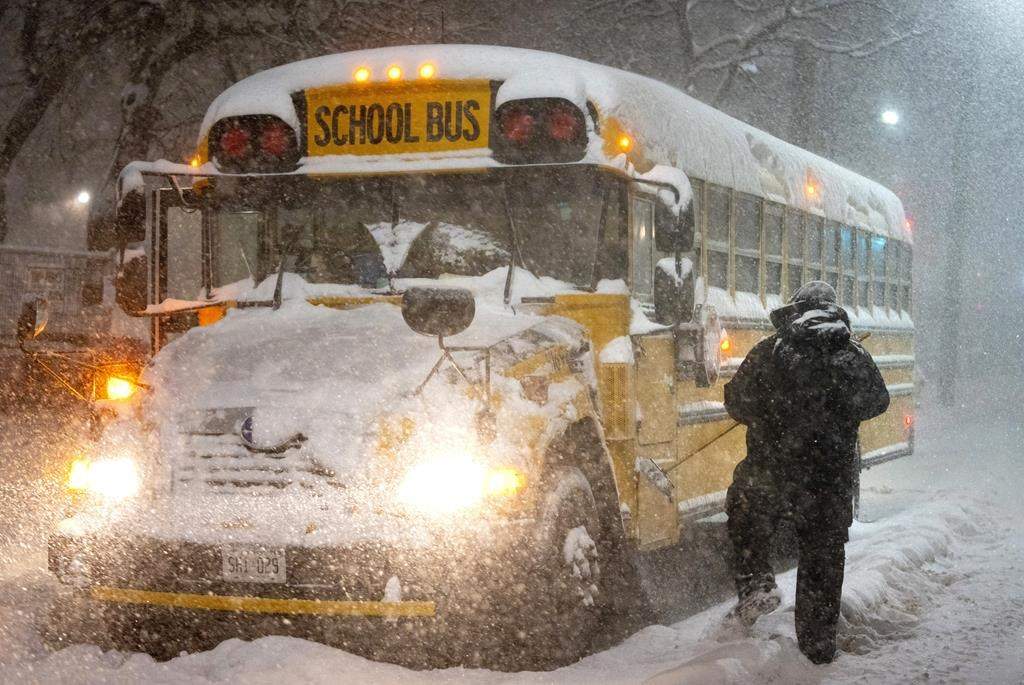 A school bus driver tries to clear snow during winter storm