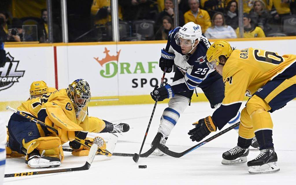 Winnipeg Jets center Paul Stastny (25) attempts to get a shot off between Nashville Predators goaltender Juuse Saros (74) and center Mikael Granlund (64) during the first period of an NHL hockey game Thursday, Jan. 20, 2022, in Nashville, Tenn. (AP Photo/Mark Zaleski)