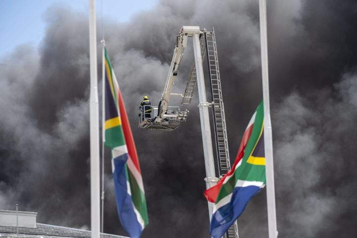 Firemen spray water on flames erupting from a building at South Africa’s Parliament in Cape Town Sunday Jan. 2, 2022.