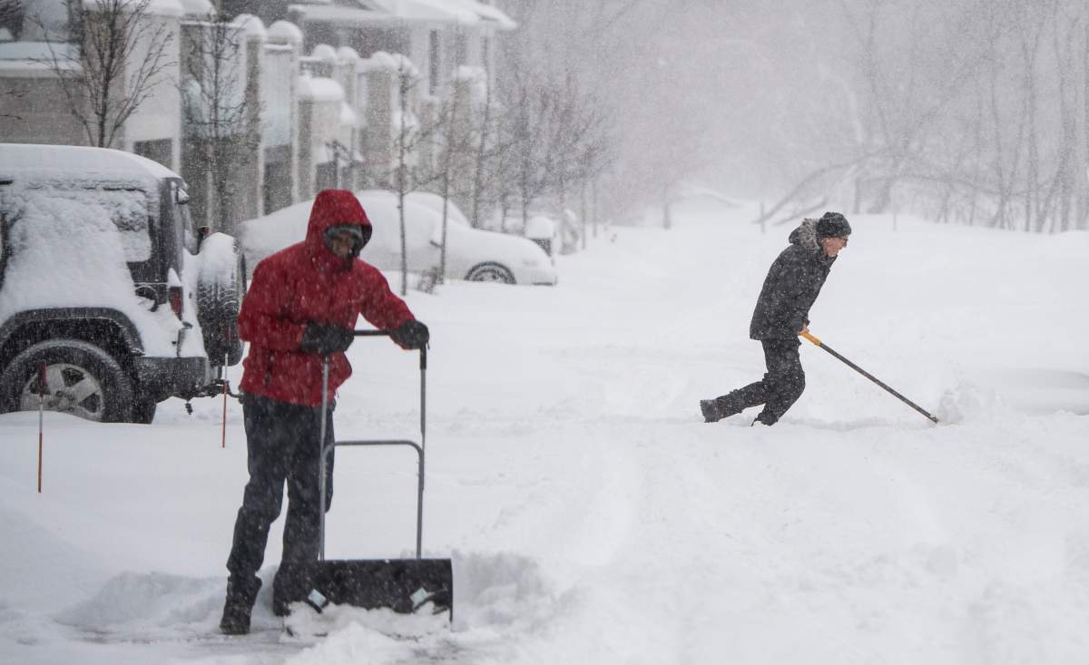 People work to clear their driveways as heavy snow continues to fall in Ottawa, on Monday, Jan. 17, 2022. A blizzard warning is in effect for the region with Environment Canada predicting between 25 to 40 cm of snow. THE CANADIAN PRESS/Justin Tang