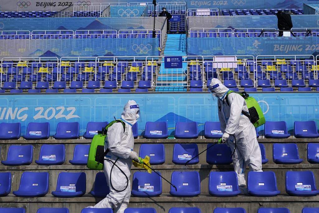 Workers in protective gear disinfect seats following the men’s freestyle skiing big air finals of the 2022 Winter Olympics, Wednesday, Feb. 9, 2022, in Beijing.