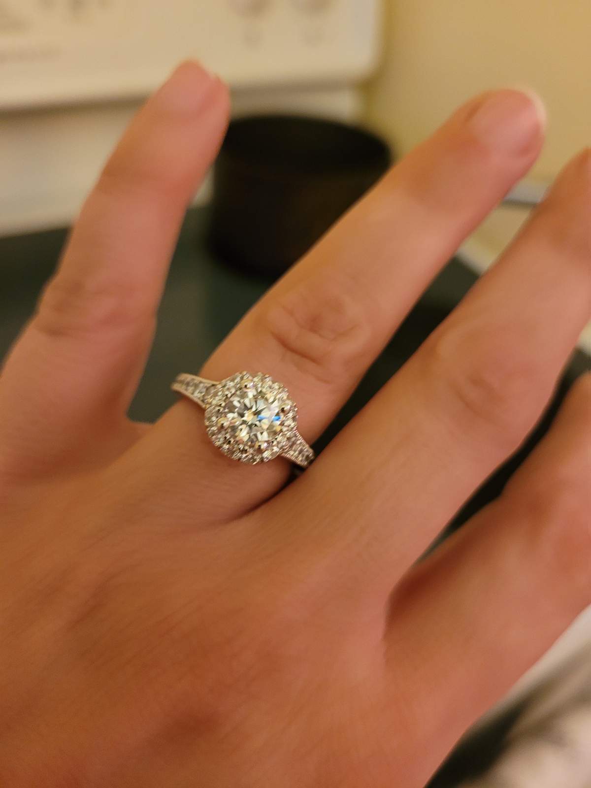 A woman's left hand showing off a diamond ring.