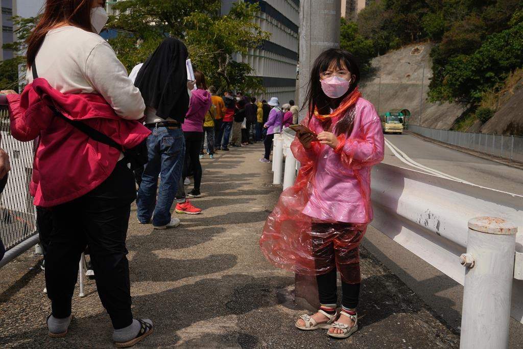 Residents line up to get tested for the coronavirus at a temporary testing center for COVID-19, in Hong Kong, Tuesday, Feb. 15, 2022.