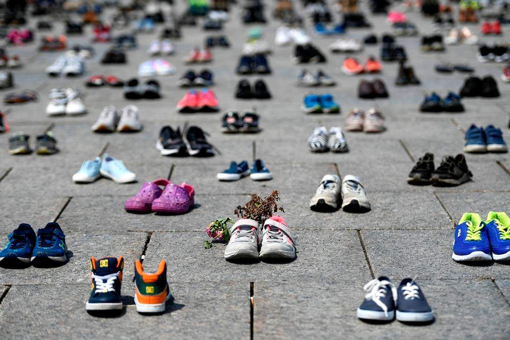 Dried flowers rest inside a pair of child's running shoes at a memorial for the 215 children whose remains were found at the grounds of the former Kamloops Indian Residential School at Tk’emlups te Secwépemc First Nation in Kamloops, B.C., on Parliament Hill in Ottawa on Friday, June 4, 2021. A British Columbia First Nation located off coast of northeastern Vancouver Island says it has started an investigation into the grounds of a former residential institution, following similar inquiries by a number of nations across the country. THE CANADIAN PRESS/Justin Tang.