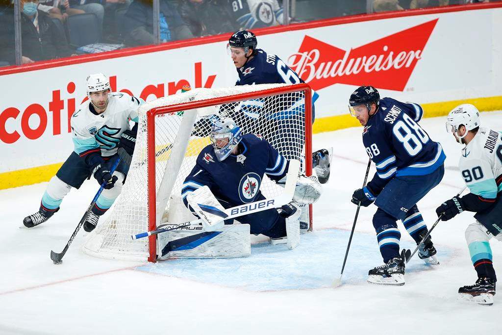 Seattle Kraken’s Jordan Eberle (7) looks for Marcus Johansson (90) as he attempts to make a pass in front of Winnipeg Jets goaltender Eric Comrie (1) during second-period NHL action in Winnipeg on Thursday, Feb. 17, 2022. THE CANADIAN PRESS/John Woods