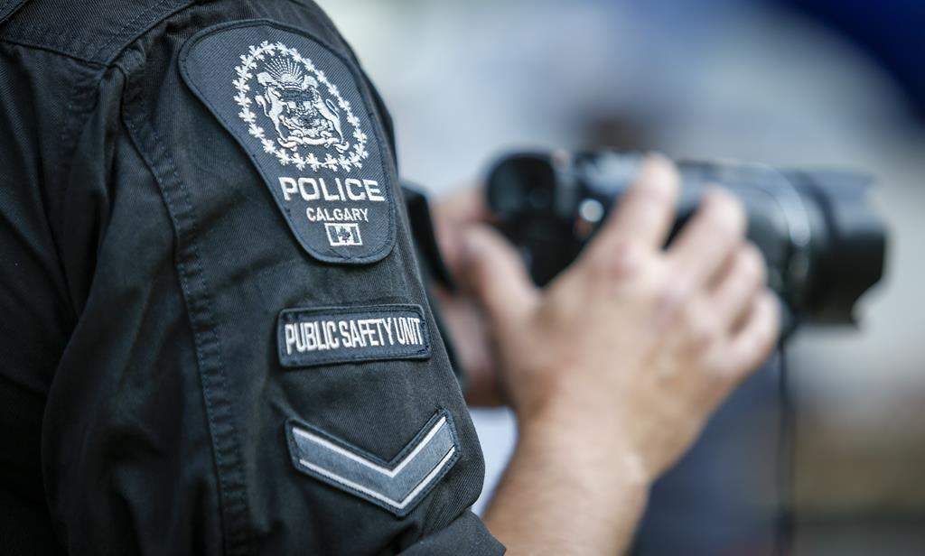 A police officer records the crowd as Alberta Premier Jason Kenney holds the premier's annual Stampede breakfast in Calgary on Monday, July 12, 2021. A group of Albertan volunteers launched a searchable police misconduct database on Tuesday. THE CANADIAN PRESS/Jeff McIntosh.