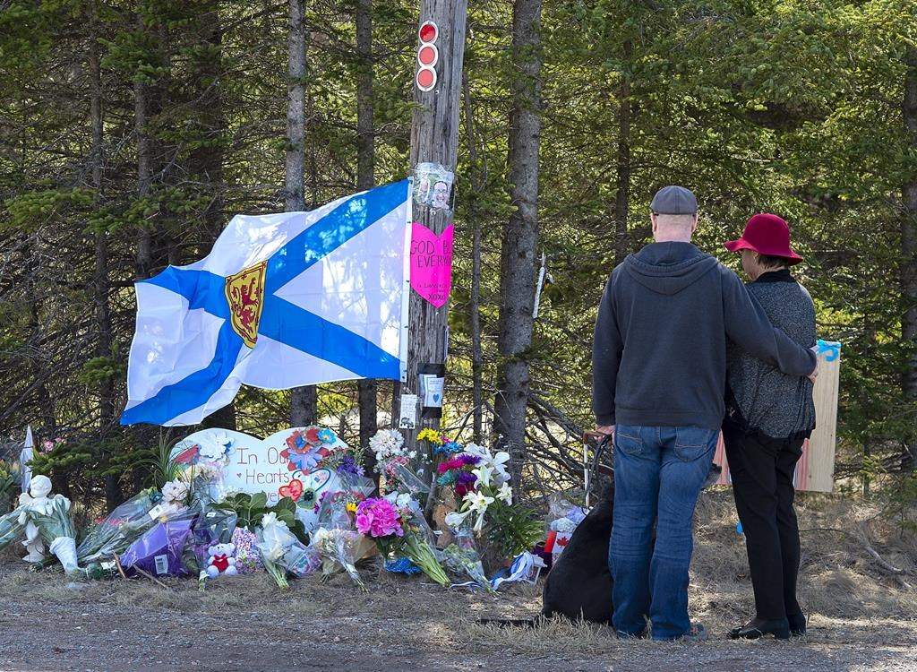 A couple pays their respects at a roadblock in Portapique, N.S. on Wednesday, April 22, 2020.