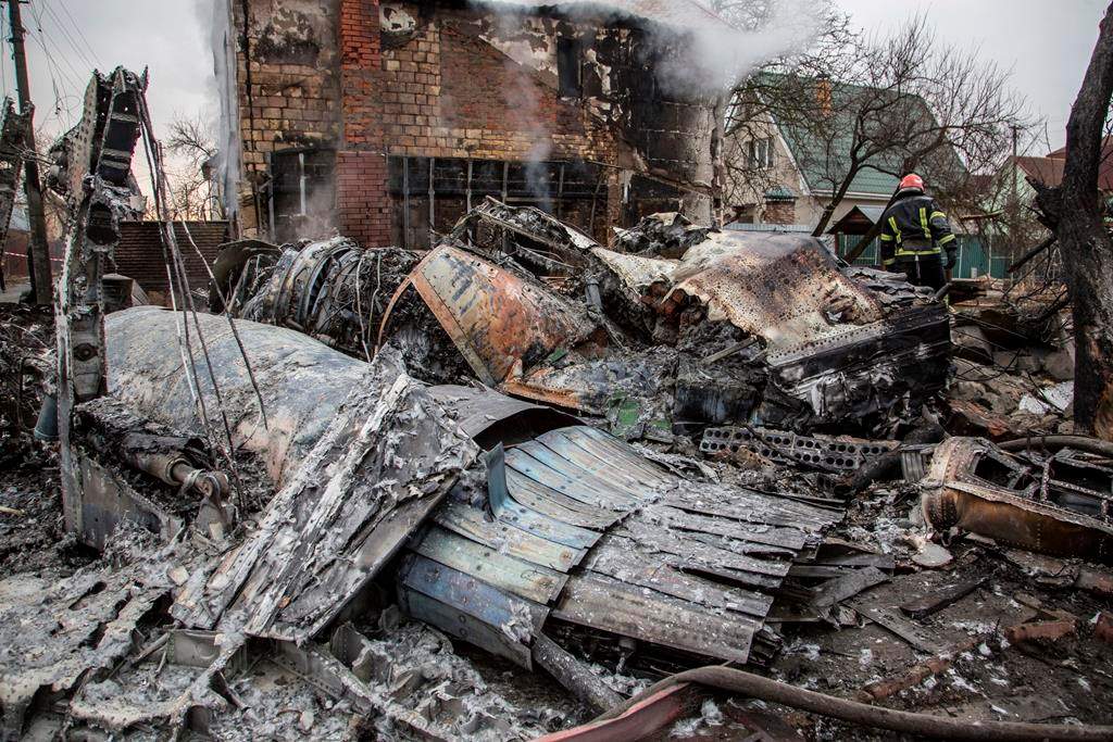 A Ukrainian firefighter walks between fragments of a downed aircraft in Kyiv, Ukraine, on Feb. 25. It was unclear what aircraft crashed and what brought it down amid the Russian invasion in Ukraine.