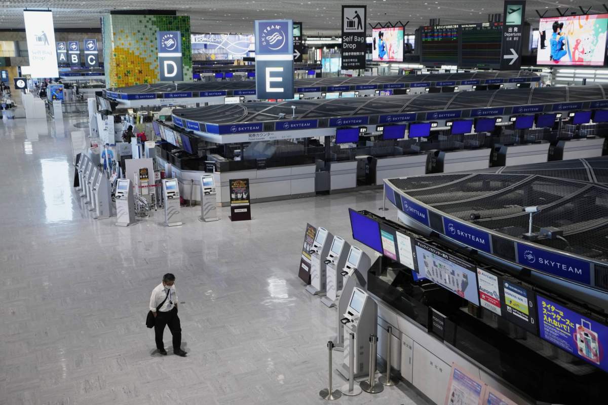 A passenger walks through the ticketing counter floor for international flights at the Narita International Airport in Narita, east of Tokyo, Thursday, Dec. 2, 2021. Japan says it has retracted a ban on new incoming international flight bookings to defend against the new variant of the coronavirus only a day after the policy was announced, following criticisms that it was an overreaction.(AP Photo/Hiro Komae).