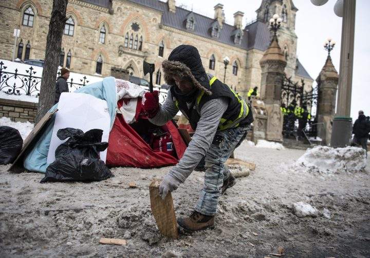 A person uses a hatchet to chop firewood for a campfire on Wellington Street in front of Parliament Hill as a rally against COVID-19 restrictions, which began as a cross-country convoy protesting a federal vaccine mandate for truckers, continues in Ottawa, on Monday, Jan. 31, 2022.