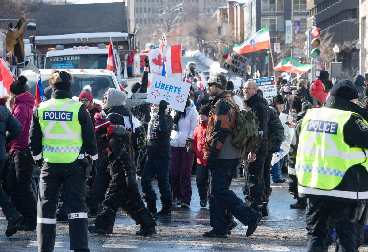 Police officers direct the demonstrators as they walk to the Quebec legislature in protest against COVID-19 restrictions, in Quebec City, Saturday, Feb. 5, 2022.
