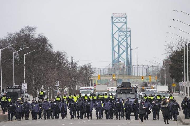 Police walk the line to remove all truckers and supporters from the Ambassador Bridge, linking Detroit and Windsor, Ont., Sunday, Feb. 13, 2022.