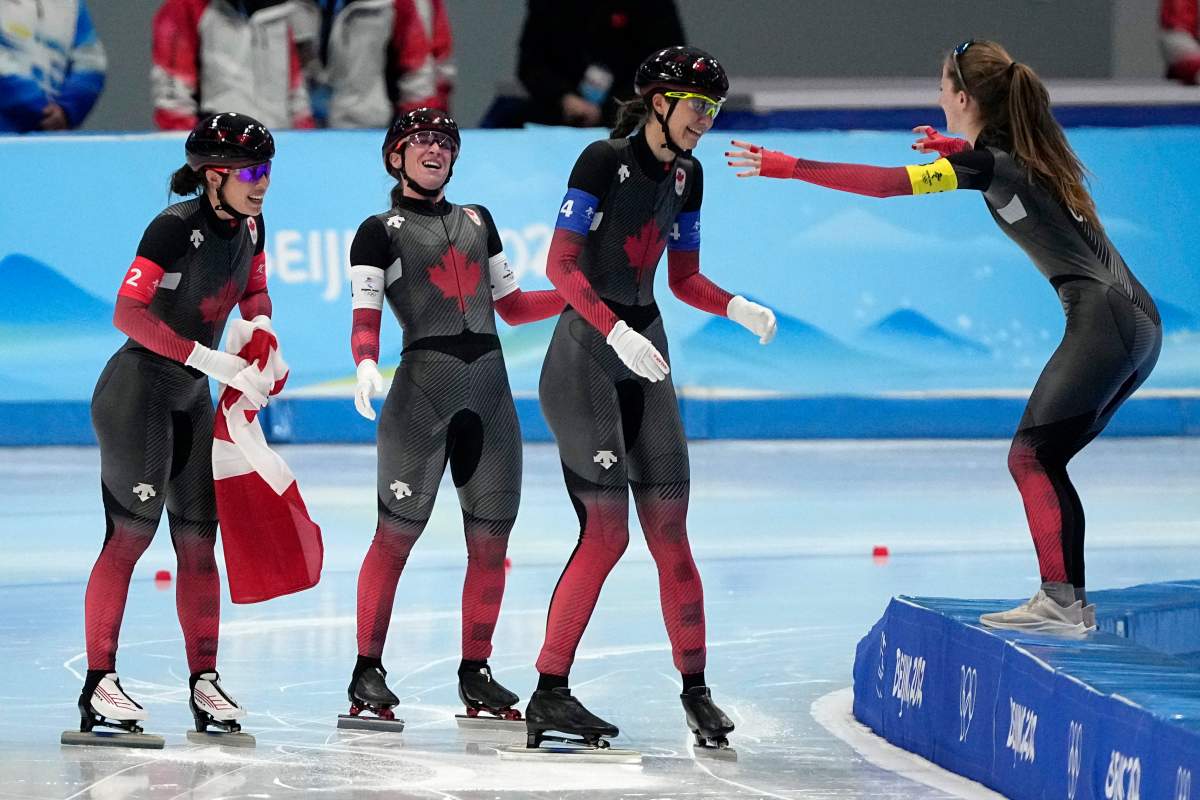 Team Canada’s Alexa Scott, right, reaches out to Isabelle Weidemann, centre, Ivanie Blondin and Valerie Maltais, left, after they won the gold medal and set an Olympic record in the speed skating women’s team pursuit finals at the 2022 Winter Olympics on Feb. 15 in Beijing.