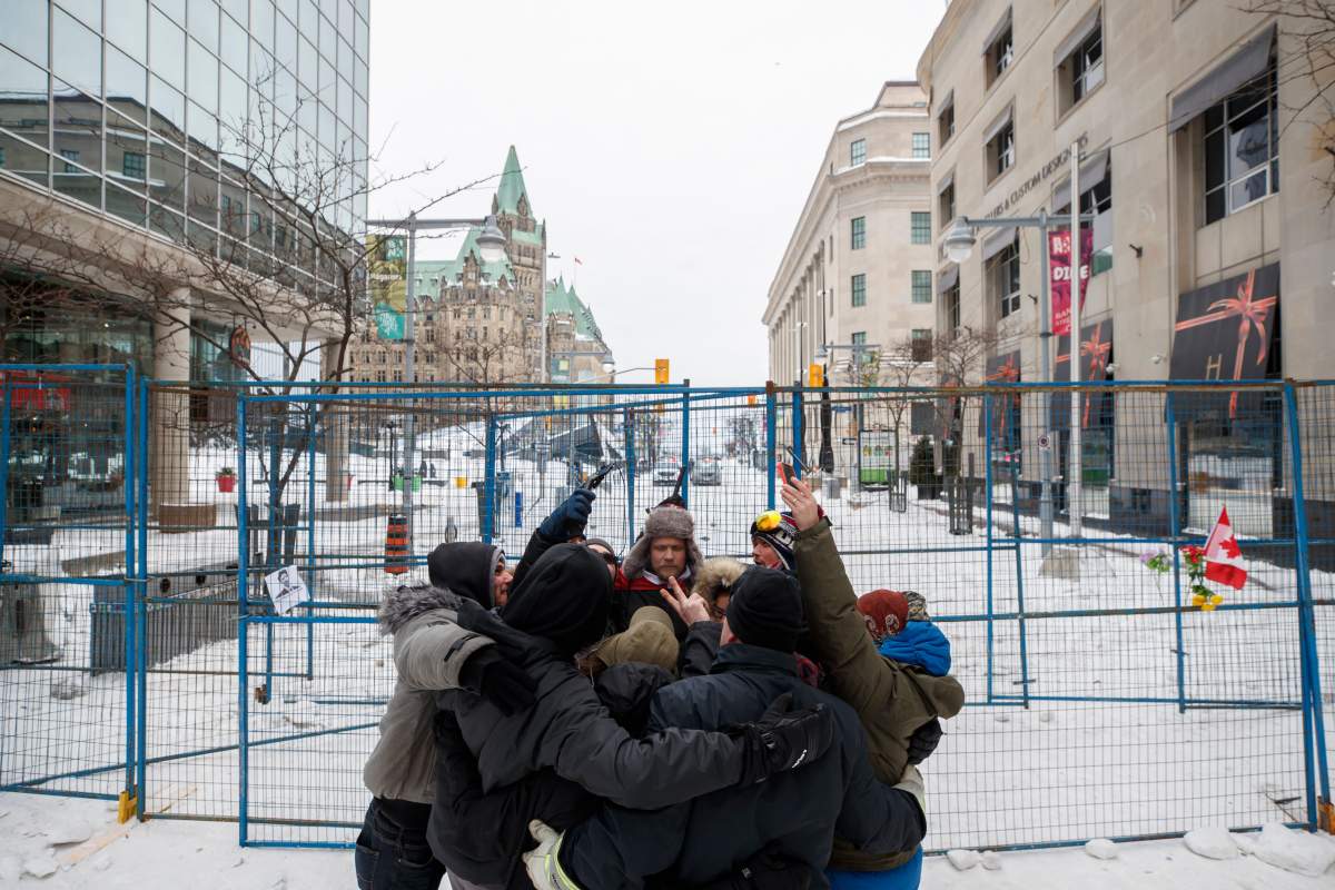 People hug outside of a fenced off portion of downtown Ottawa on Sunday, Feb. 20, 2022, after police worked to clear a trucker protest that was aimed at COVID-19 measures that grew into a broader anti-government protest. THE CANADIAN PRESS/Cole Burston