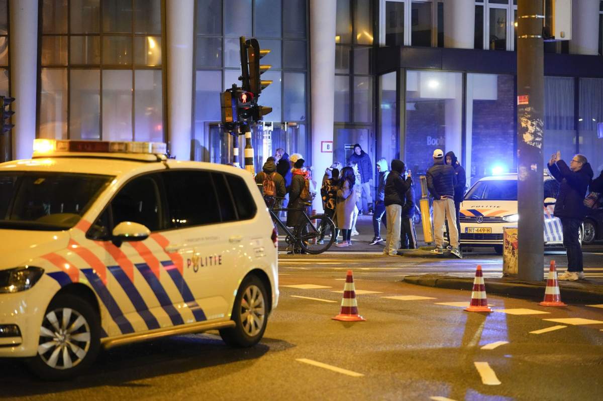 Police vehicles cordon off a wide area in Amsterdam, Netherlands, Tuesday, Feb. 22, 2022, where an armed person is holed up in the Amsterdam Apple Store with at least one hostage in an hours-long standoff with scores of police massed outside. (AP Photo/Peter Dejong).