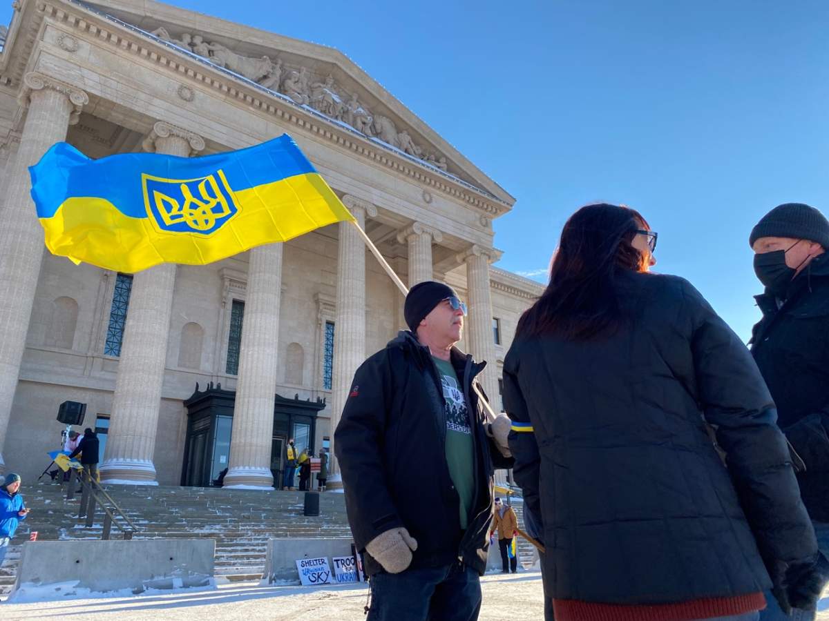 A man holding the Ukrainian flag emblazoned with the coat of arms of Ukraine during a rally in Winnipeg Saturday.