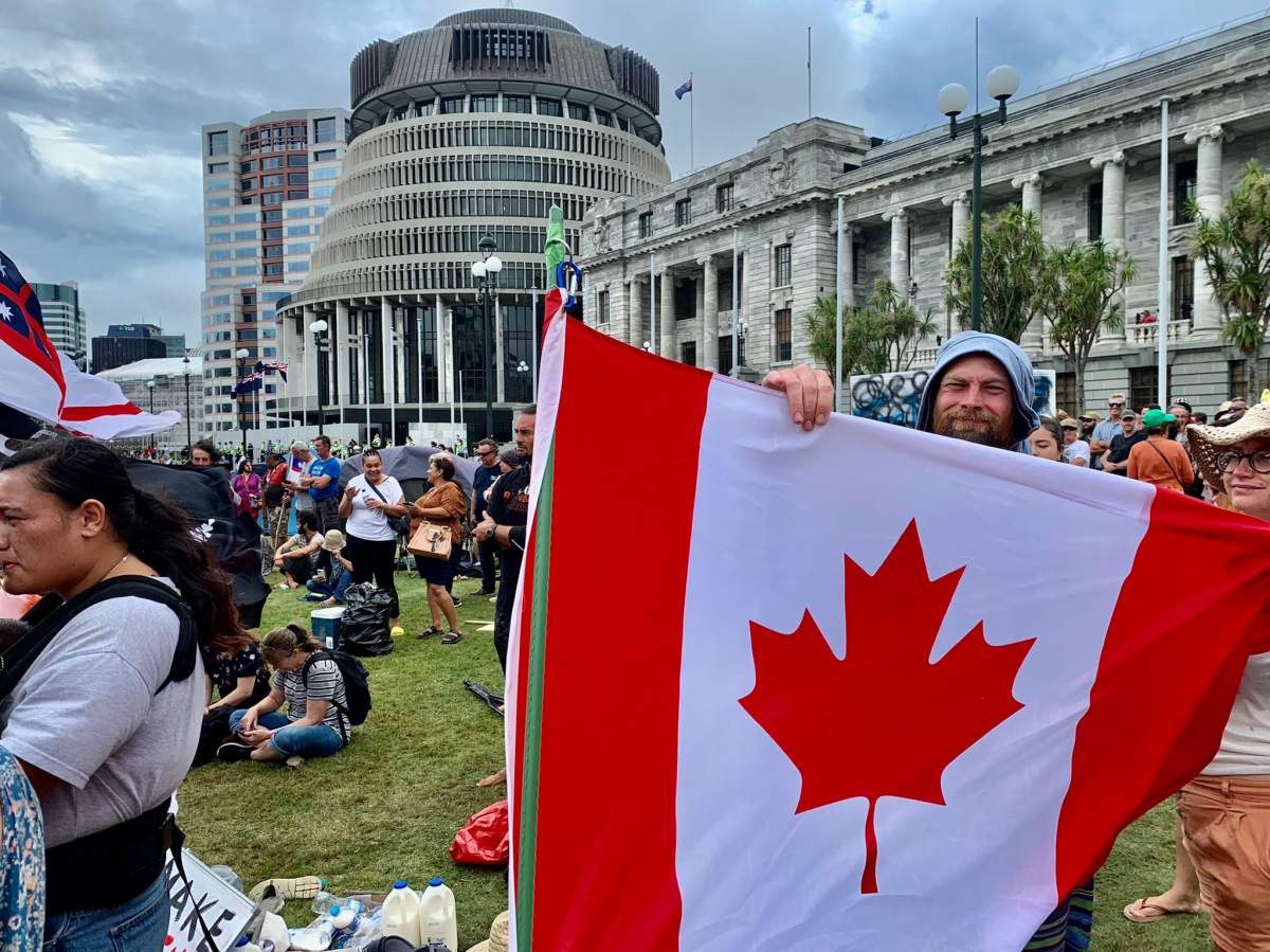 A New Zealand protester holding the Canadian flag during an anti-vaccine campout on Parliament grounds.