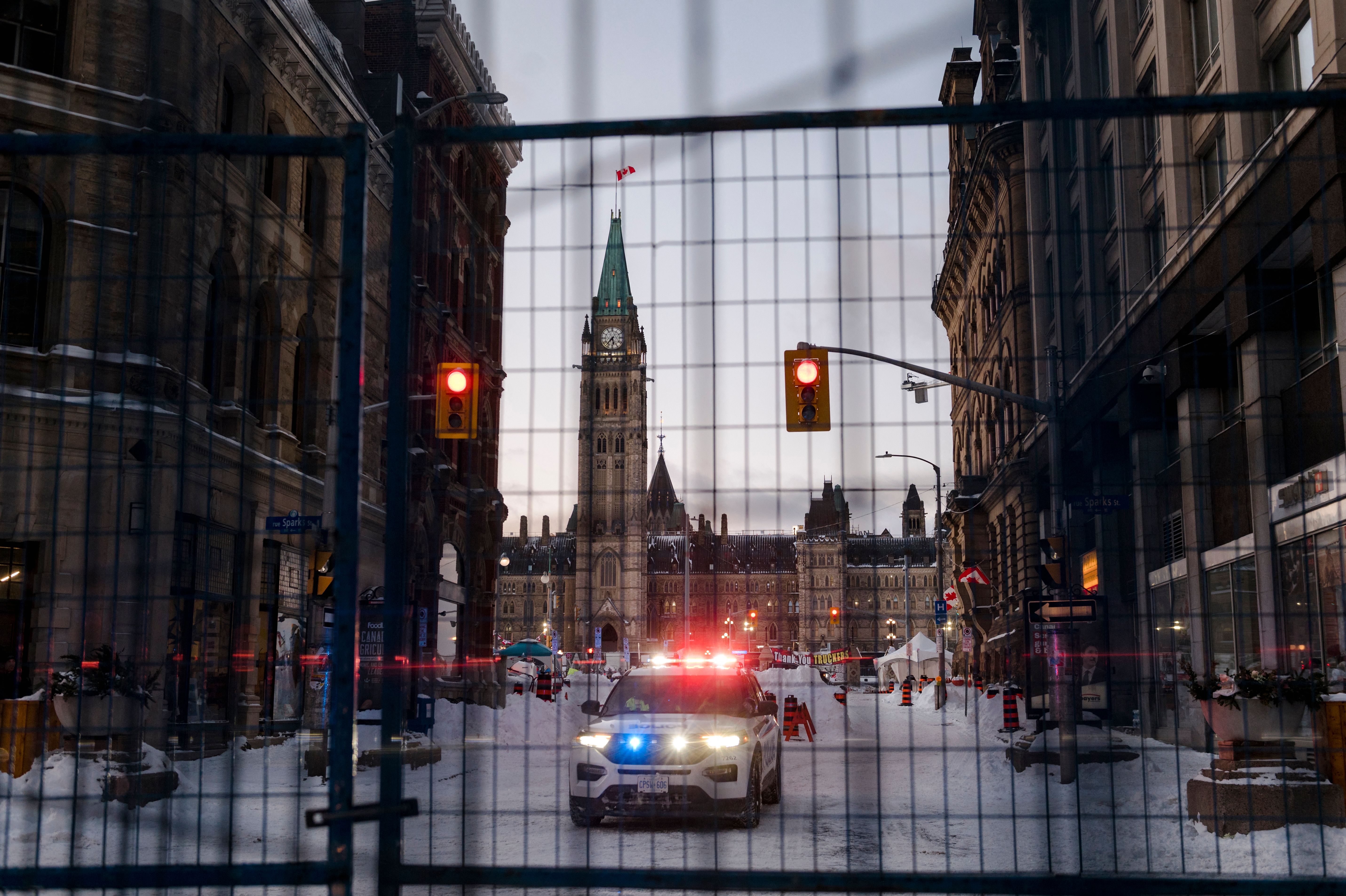 A police car is seen behind a barrier in front of Parliament Hill after police cleared Wellington Street, previously occupied by the Freedom Convoy, in Ottawa, on February 19, 2022. - Ottawa Police Services barricaded Wellington St. around Parliament Hill, clearing up the trucks and the camps that had been in Ottawa since January 28, 2022.  (Photo by Andrej Ivanov / AFP) (Photo by ANDREJ IVANOV/AFP via Getty Images).