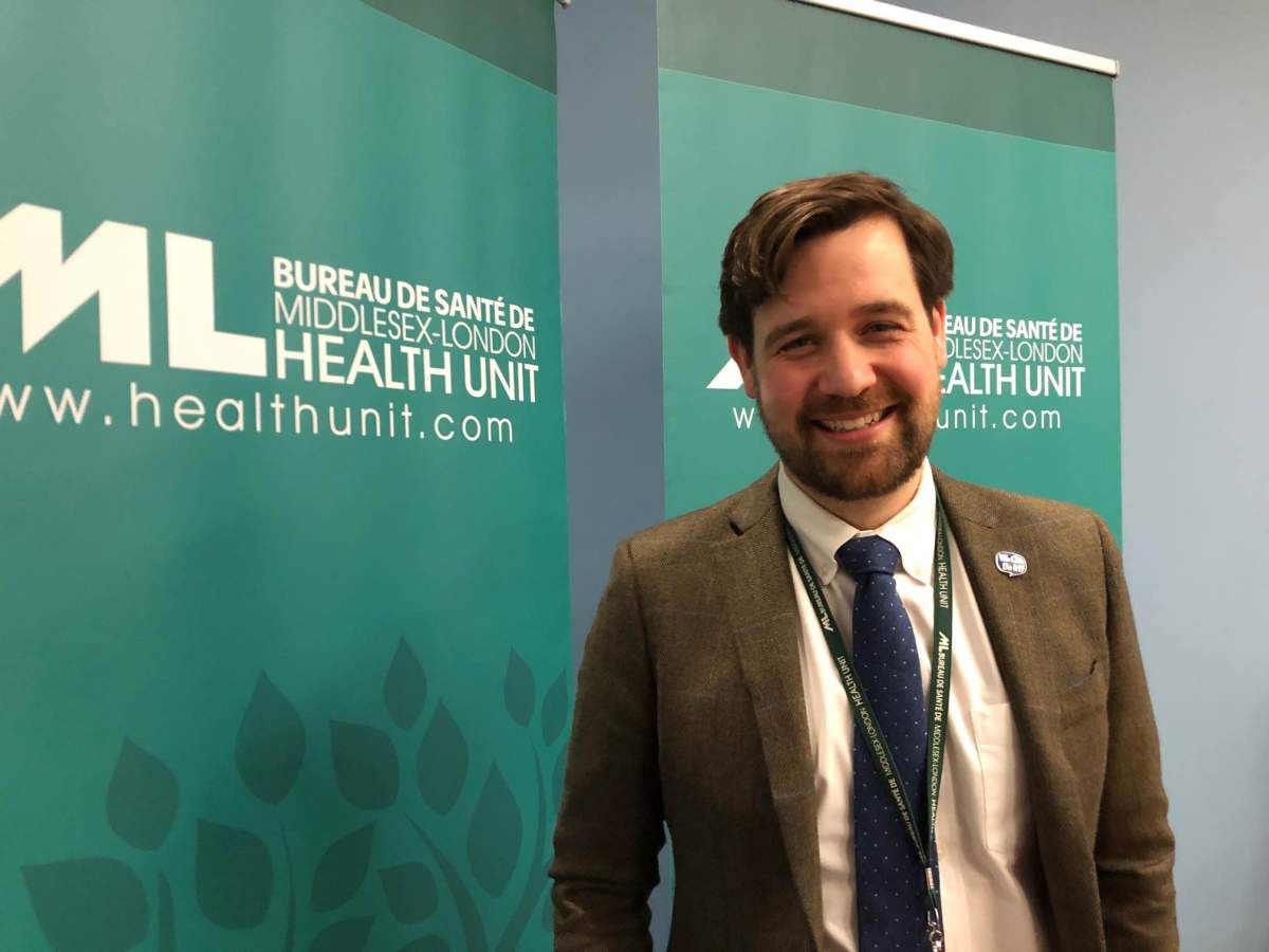 Dr. Alex Summers Stands and smiles wearing a brown suit