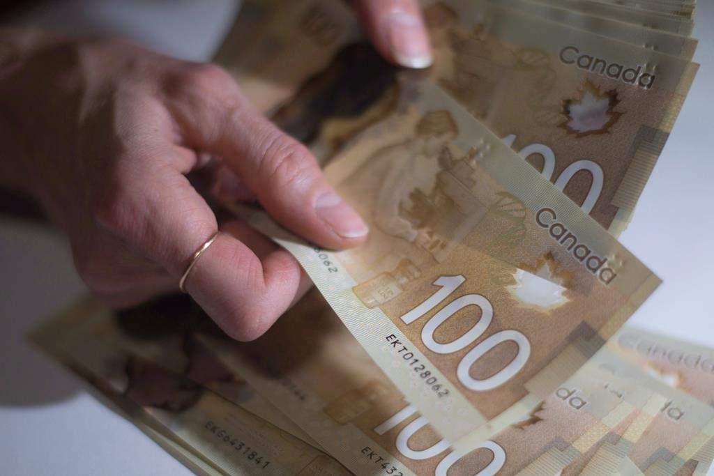 Statistics Canada says the ratio of household debt to disposable income hit a record level in the fourth quarter as mortgage borrowing rose and disposable income fell. Canadian $100 bills are counted in Toronto, Feb. 2, 2016.  THE CANADIAN PRESS/Graeme Roy.