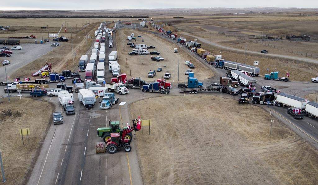 Demonstrators protesting vaccine mandates and other pandemic restrictions gather as part of a truck convoy blocking the highway at the busy U.S. border crossing near Coutts, Alta.,on Monday, Jan. 31, 2022.