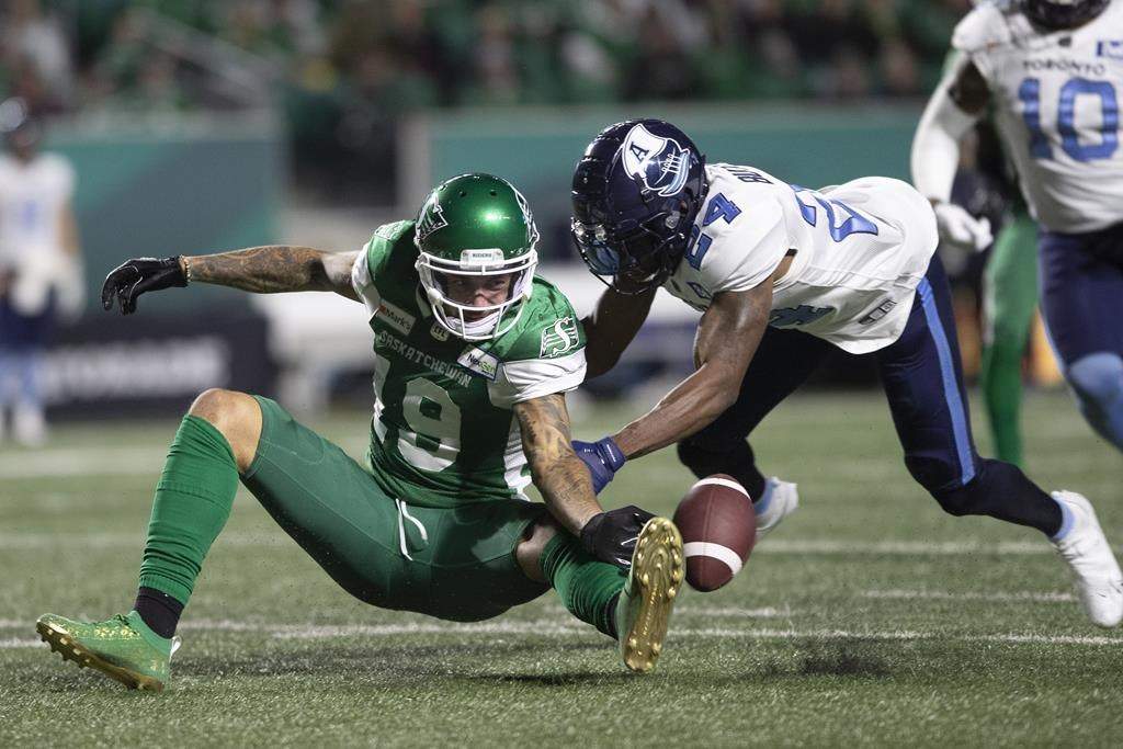 Saskatchewan Roughriders wide receiver Brayden Lenius (19) is hit by Toronto Argonauts defensive back Crezdon Butler (24) during the first half of CFL football action in Regina on Sept. 17, 2021. THE CANADIAN PRESS/Kayle Neis