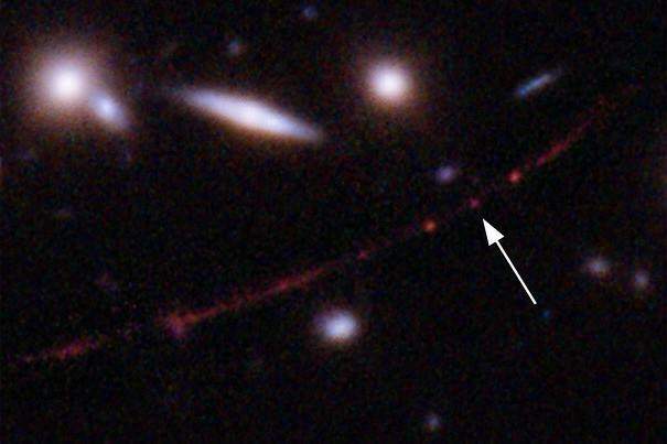 This image made available by NASA on Wednesday, March 30, 2022, shows the star Earendel, indicated by arrow, and the Sunrise Arc galaxy, stretching from lower left to upper right, optically bent due to a massive galaxy cluster between it and the Hubble Space Telescope which captured the light. 