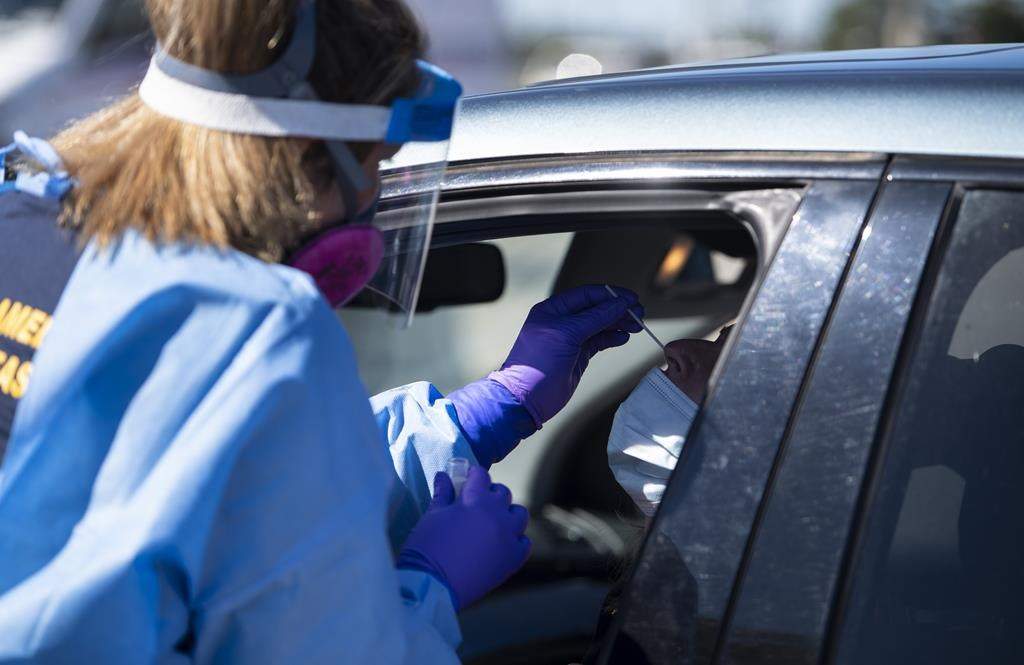 Paramedic Jessica Aiken administers a nasal swab at a drive through, pop-up COVID-19 test centre outside the Canadian Tire Centre in Ottawa, Sunday, Sept. 20, 2020. 