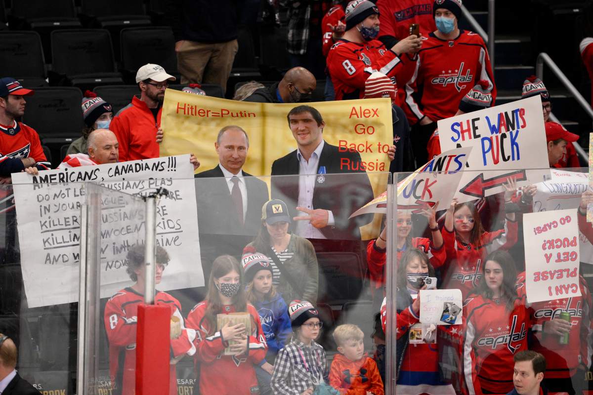 A sign is held up showing Vladimir Putin and Washington Capitals’ Alex Ovechkin during warmups before an NHL hockey game between the Capitals and the Seattle Kraken, Saturday, March 5, 2022, in Washington.