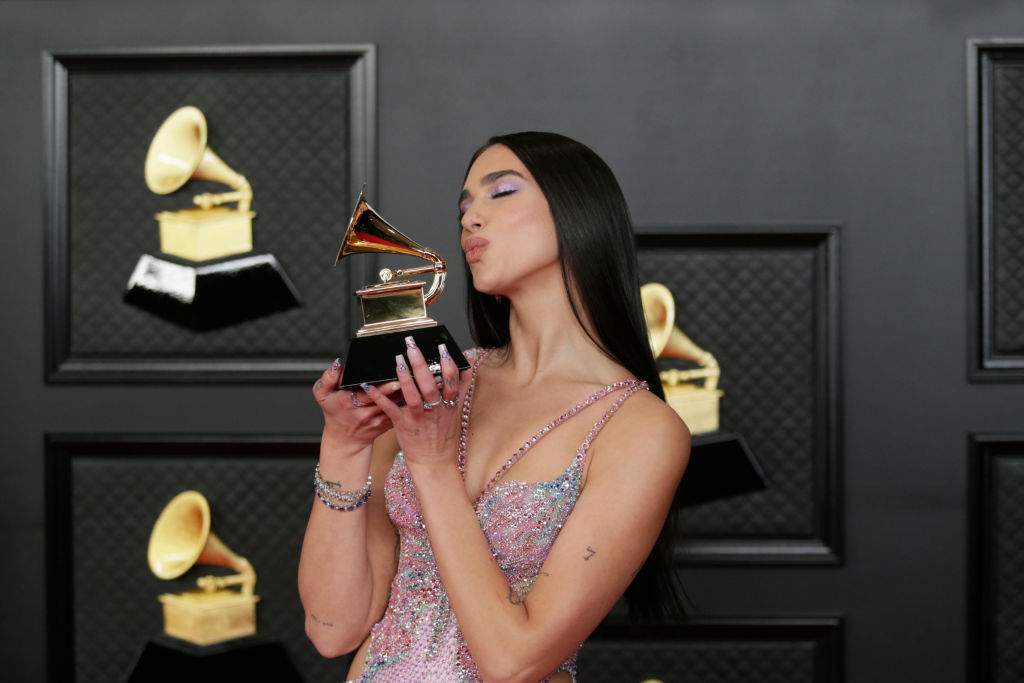 Dua Lipa holding a Grammy and making a kissing face.