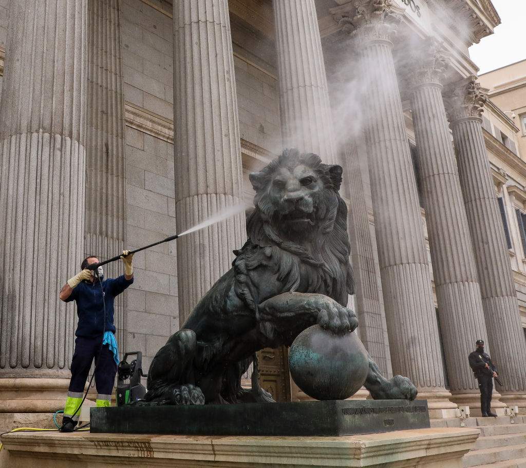 A worker cleans the lion of the Spanish Congress building which is covered with Saharan dust