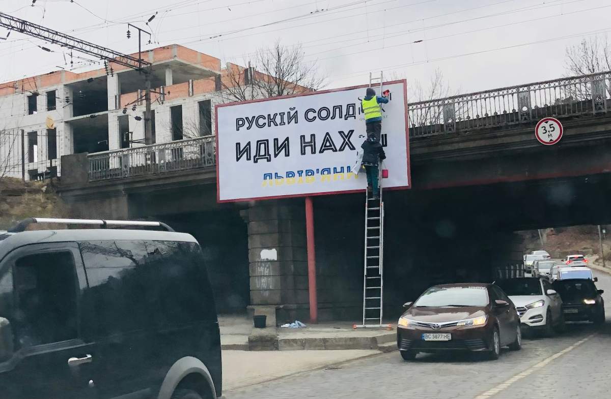A worker hangs a sign taunting Russian forces, Lviv, Ukraine, March 7, 2022.