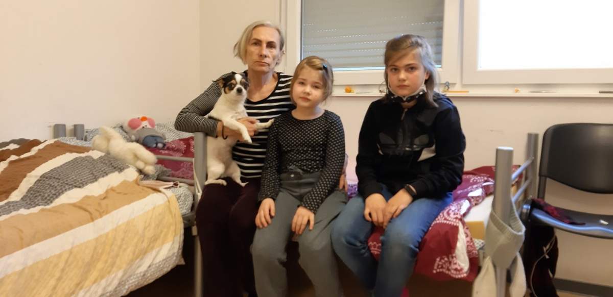 Tamara Bakum sits with her two grandchildren in a refugee camp in Germany, holding their family dog.