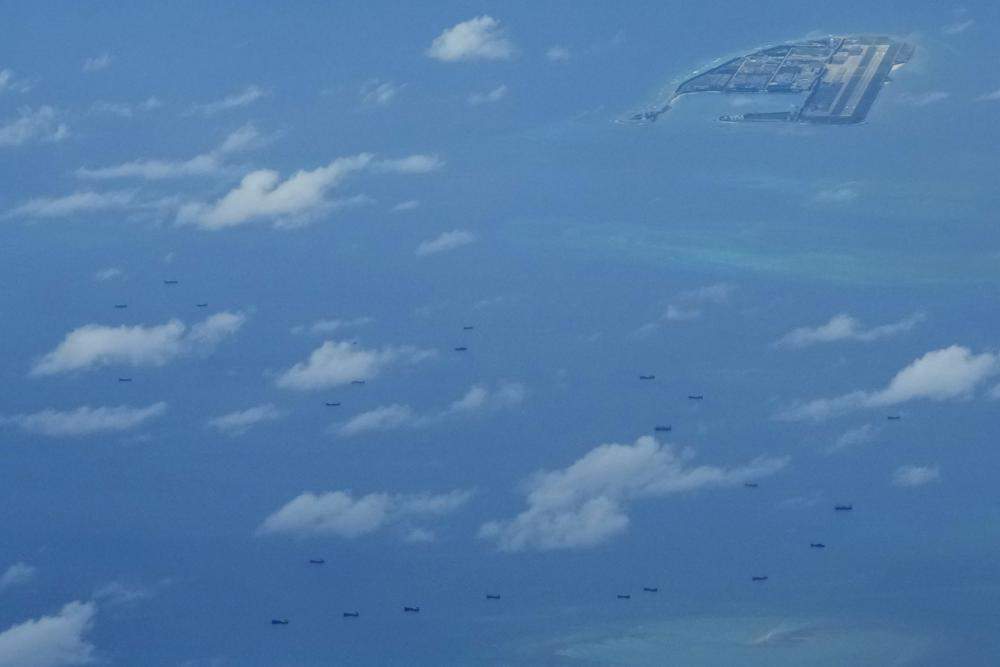 Boats are seen beside Chinese structures and buildings on the man-made Fiery Cross Reef at the Spratlys group of islands in the South China Sea on Sunday March 20, 2022. (AP Photo/Aaron Favila)