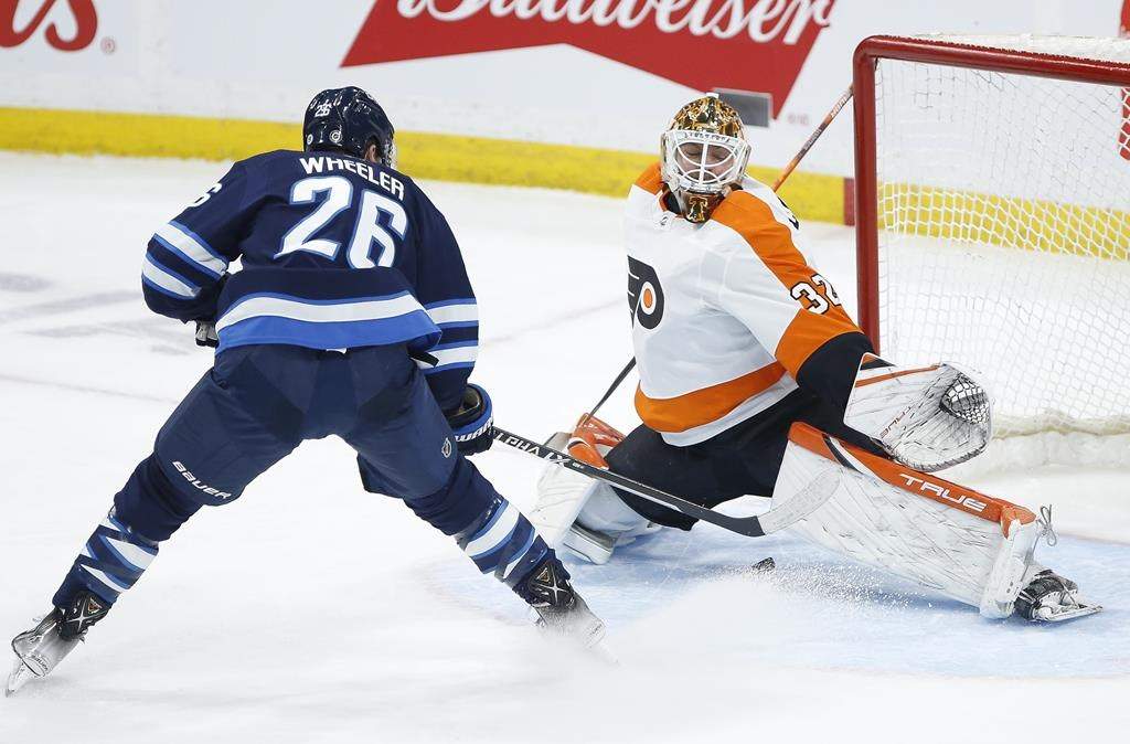 Winnipeg Jets’ Blake Wheeler (26) slides the puck between the legs of Philadelphia Flyers goaltender Felix Sandstrom (32) for the goal during second-period NHL action in Winnipeg on April 27, 2022.