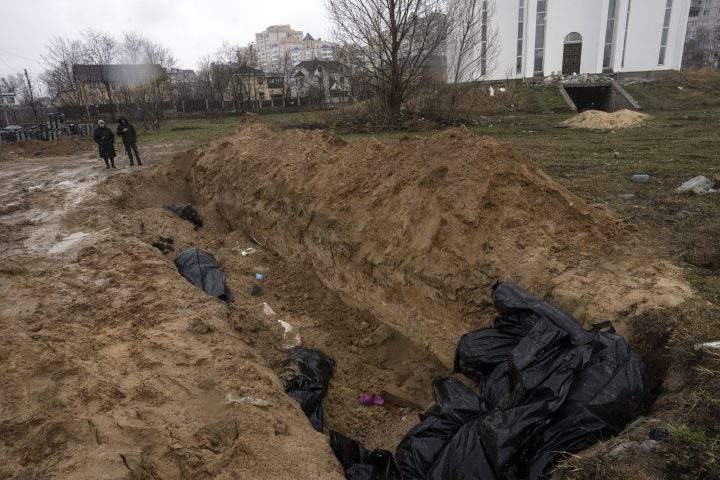 Neighbours gather next to a mass grave in Bucha, in the outskirts of Kyiv, Ukraine, Sunday, April 3, 2022.